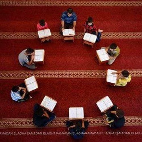 حلقة تحفيظٍ في المسجد، طلابٌ يجلسون في دائرةٍ أمام رحلاتٍ خشبية