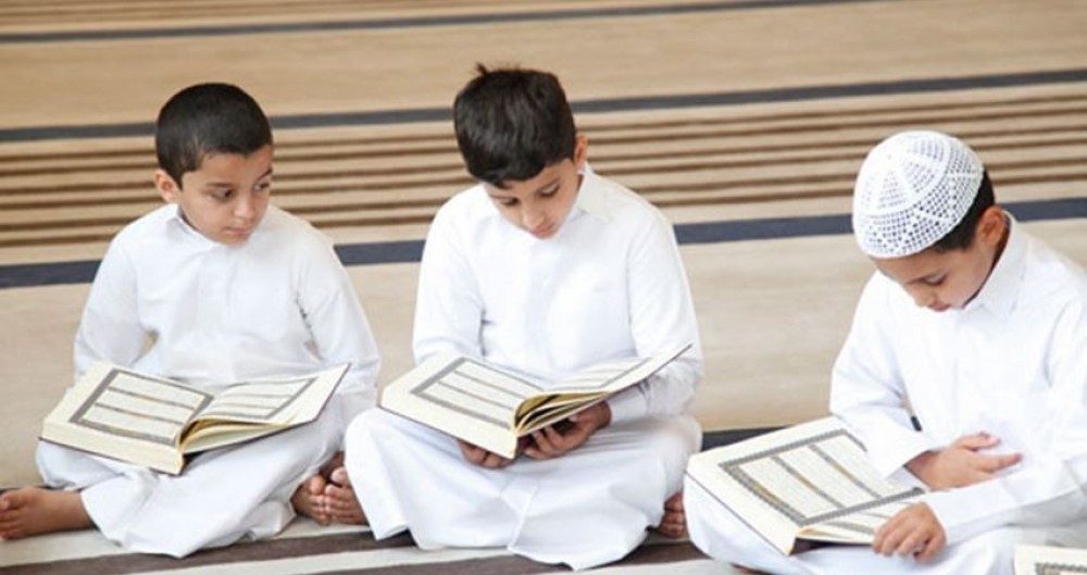 ثلاثة طلابٍ يقرؤون في المصاحف داخل حلقة تحفيظ